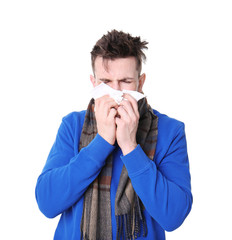 Young man with cold sneezing on white background