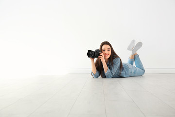 Female photographer with camera lying on floor indoors - Powered by Adobe