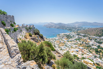 Fototapeta na wymiar Beautiful sunny village town Panteli harbor view to the greek blue sea water from the old castle with boats cruising surrounded mountains, Medieval Castle, Leros, Dodecanese Islands, Greece 