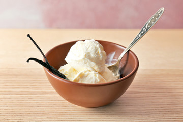 Bowl with tasty vanilla ice cream on wooden table