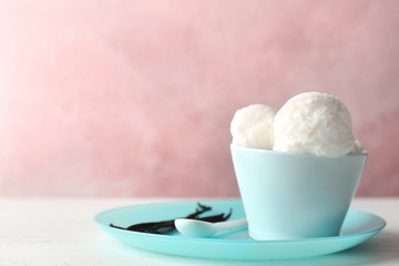 Bowl with tasty vanilla ice cream on table