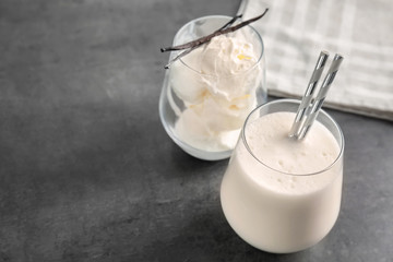 Glasses with milk shake and tasty vanilla ice cream on grey background