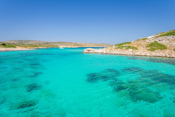 Beautiful sunny coast view to a small greek island bays and crystal clear blue water beach like paradise with some boats cruising or fishing, Arki, Tiganakia Beach, Leros, Dodecanese/ Greece 