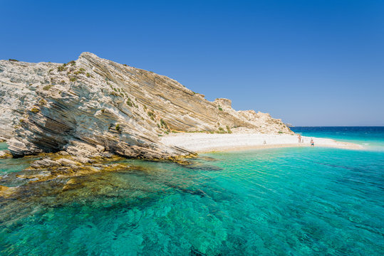 Beautiful sunny coast view to a small greek island and crystal clear blue water beach with some boats cruising and people swimming, White Island, Aspronisi, Leros, Dodecanese/ Greece &ndash; July 22 2017