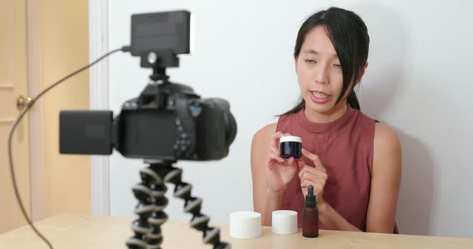 Woman showing the cosmetic product in front of the camera and take the video