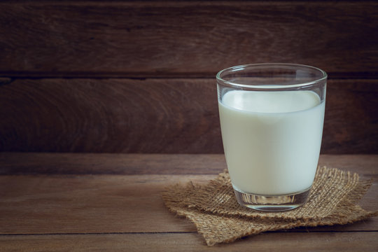 Glass of milk on wooden background.