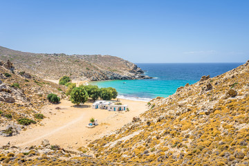 Beautiful sunny coast view to the greek beach Psili Ammos and blue aegean sea with crystal clear water sandy beach with some boats fishing cruising small hills covering, Patmos, Dodecanese, Greece 