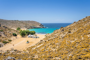 Beautiful sunny coast view to the greek beach Psili Ammos and blue aegean sea with crystal clear water sandy beach with some boats fishing cruising small hills covering, Patmos, Dodecanese, Greece 