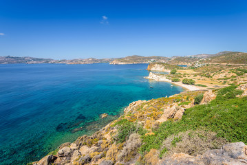 Fototapeta na wymiar Amazing sunny coast view to a empty holiday bay Didymes beach with crystal clear blue water sandy beach for sunbathing and some boats cruising fishing in background, Patmos Island, Dodecanese, Greece