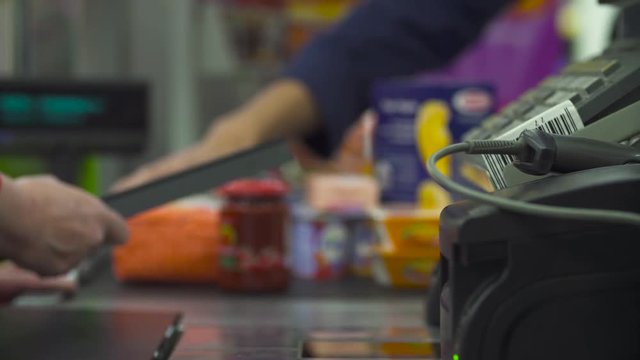 Close up check out counter. Senior female hands working on cash register in the supermarket