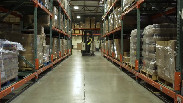 Two workers using forklifts in a warehouse