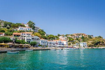 Beautiful sunny greek village town white house and harbor view to the aegean blue sea with crystal clear water and fishing boats cruising yacht white houses, Ikaria Island, Evdilos, Sporade, Greece