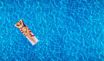 Woman in bikini on the inflatable mattress in the swimming pool.