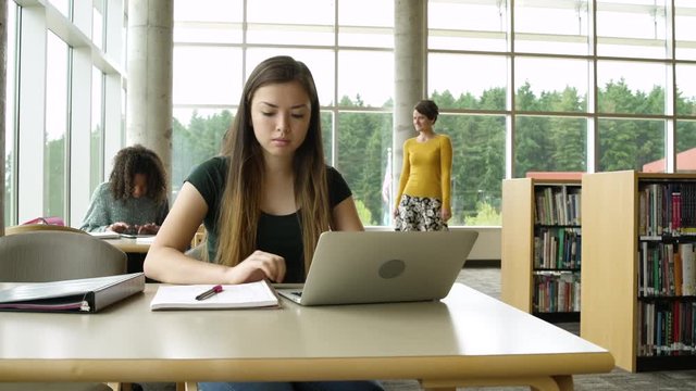 Teacher helping a female student to use a laptop