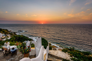 Obraz premium Beautiful colorful purple sunset sunrise coast view to a small greek town village with harbour fishing boats blue sea with crystal clear water, Ikaria Island, Armenisits, Sporades/ Greece - 08 05 2017