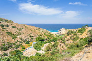 Fototapeta na wymiar Beautiful sunny summer coast view to the greek blue sea with crystal clear water sandy holiday relaxing beach with some boats fishing cruising surrounded by hills mountains, Ikaria, Sporades, Greece 