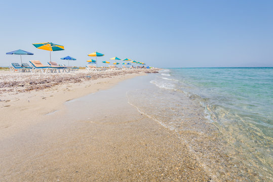 Beautiful sunny coast view to the greek beach mediterranean blue sea with crystal clear water and pure sandy beach while some tourists are sunbathing and relaxing in Marmari Tigaki