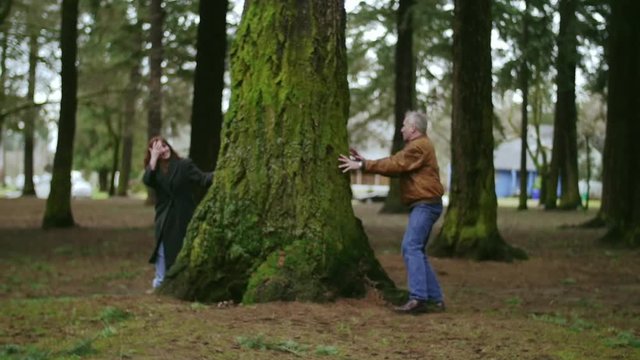 Elderly loving couple playing hide and seek at a park