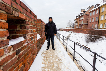 Man standing on brick wall after winter storm