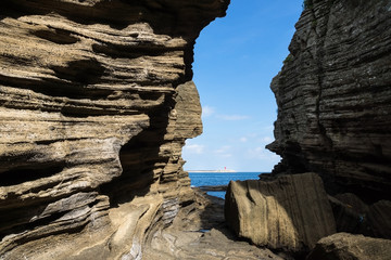 Sandstone cliffs with gap with view to ocean at Yongmeori Beach, Sanbang-ro, Jeju Island, South Korea