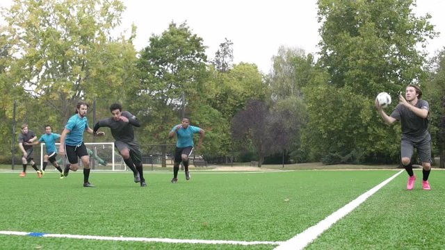 Male soccer player throwing ball onto pitch.