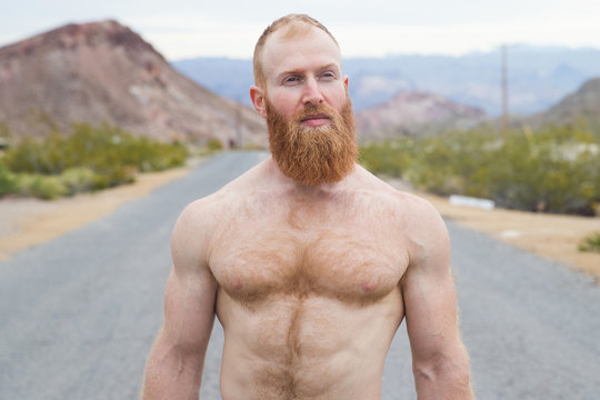 Strong, shirtless man alone on desert highway