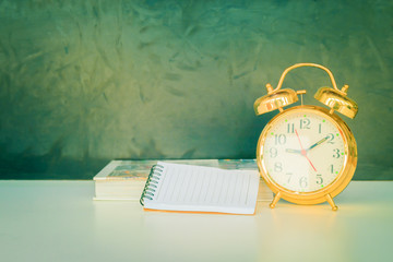 alarm clock old vintage gold and book over white on black background. with copy space add text. color cinematic Vintage style tone