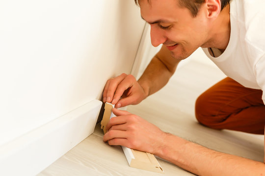 Man putting new skirting board in house