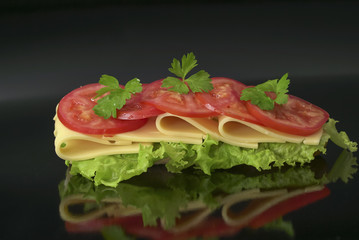fresh vegeterian sandwich with cheese, tomatoes, lettuce on dark background