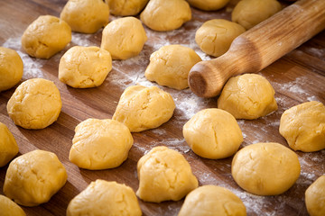 A close-up of the process of cooking buns or pancakes, next to it is a wooden rolling pin with flour on a wooden table