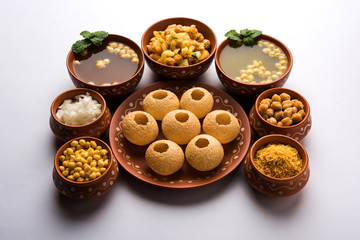 Pani Puri is Indian chat item served in a terracotta bowls and plate
