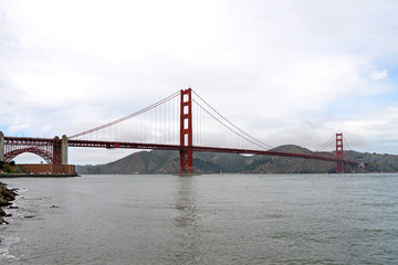 Golden Gate Bridge spans almost two miles across the Golden Gate, the narrow strait where San Francisco Bay opens to meet the Pacific ocean. Fort Mason tucked in on the left side under the arch.