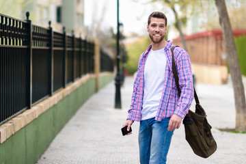 Young bearded man smiling in urban background. Lifestyle concept.