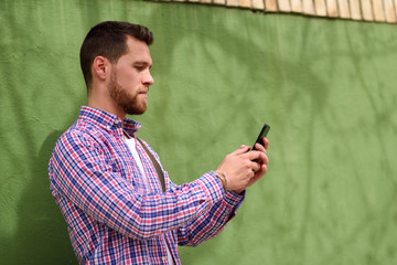 Young man looking at his smart phone in urban background. Lifestyle concept.