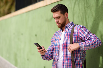 Young man looking his smart phone in urban background. Lifestyle concept.