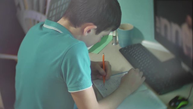 man schoolboy teenager writes does homework . boy schoolboy teenager watch social media internet video indoors education