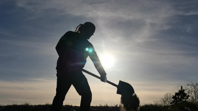 Silhouette of man digging with spade - bright sun flickering