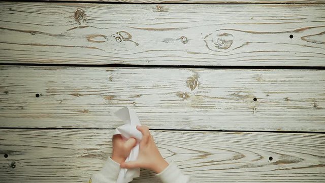 Children's hands crumple a piece of paper
