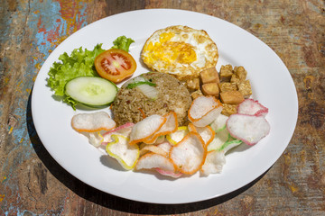 Fried rice with vegetables, rice chips, cheese tofu and fried egg on the table, close up
