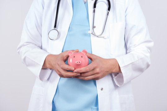 Arzt mit einem Sparschwein in den H&auml;nden