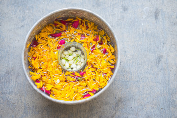 Water in bowl mixed with perfume and flowers