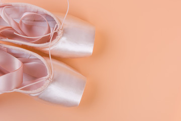 Top view of pink ballet shoes on yellow background