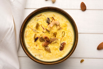 kheer or rice pudding is an Indian dessert in a brown terracotta bowl with dry fruits toppings
