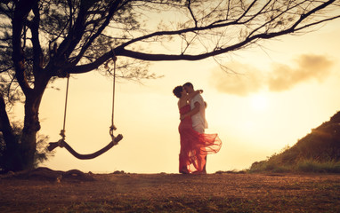 The couple is kissing. The guy makes an offer. A swing on the tree. A pair of lovers. Love.