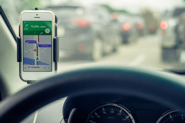 Mobile phones show traffic jam map. View from the inside of the car through the steering wheel to...