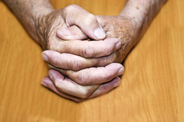 Old granny hands on a wooden close-up background