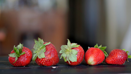 Red strawberries in a row with blurry background.