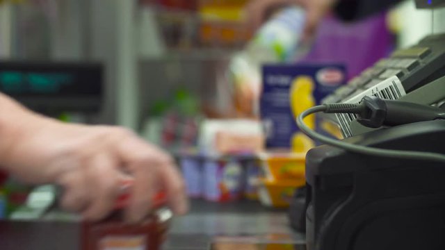 Close up check out counter. Senior female hands working on cash register in the supermarket