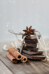 Chocolate with cinnamon sticks on vintage wooden background, selective focus