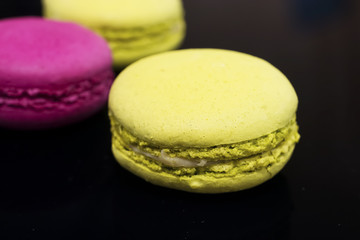 Macaroni cakes on black background. Close-up.